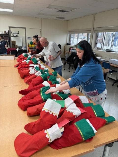 Volunteers filling rows of red and green stockings at a long table